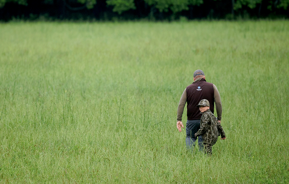 father and son walking in field